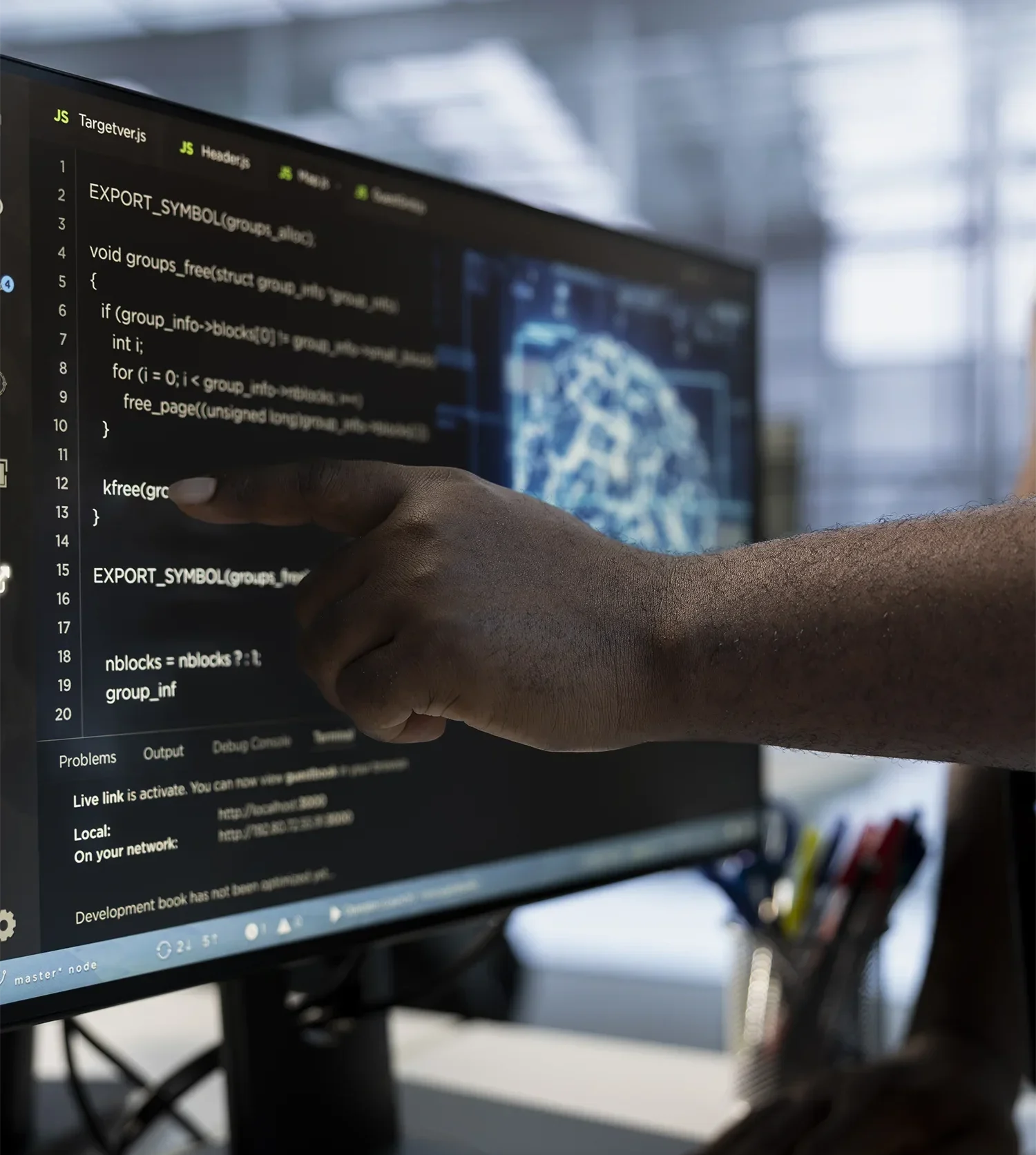 Focused coding session with a hand pointing at programming lines on a monitor